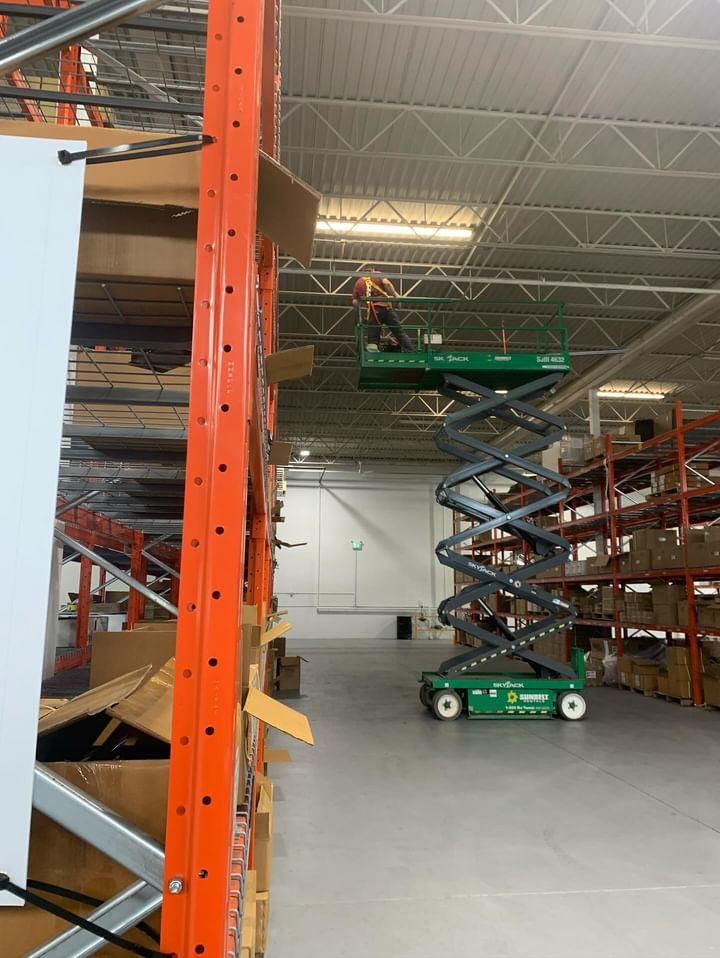 Lazo Electric electrician installing warehouse lighting from a scissor lift at Techniweld Corporation